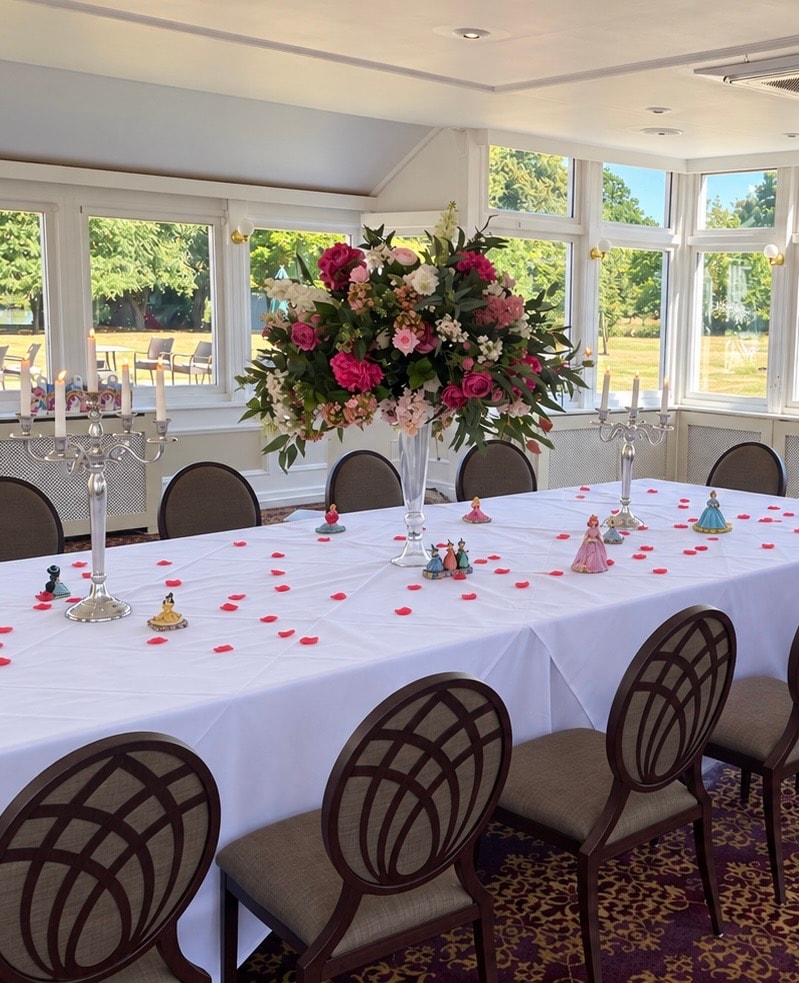 Tall floral centrepiece with roses and candles at a wedding reception